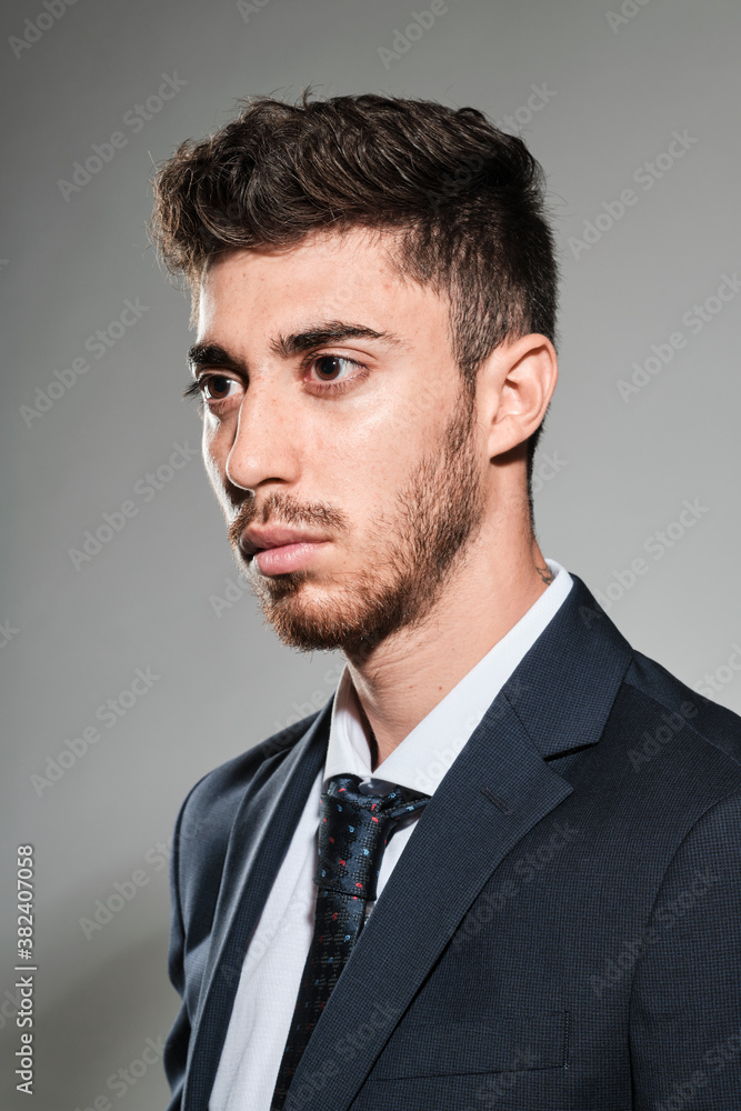 Young man portrait wearing a dark blue suit and a dark blue tie with red and light blue dots. Young man portrait wearing a dark blue suit and a dark blue tie with red and light blue dots.