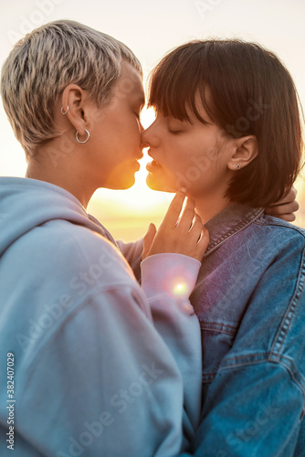 Young lesbian couple having romantic moment, Two women going to kiss while watching the sunrise together, Selective focus