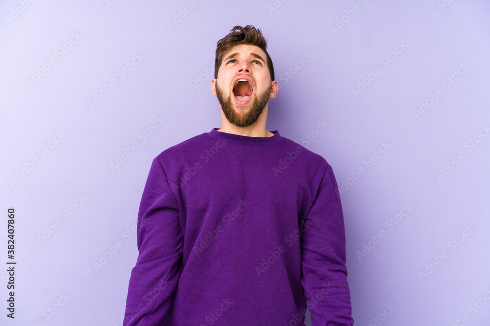 Young caucasian man isolated on purple background shouting very angry, rage concept, frustrated. Young caucasian man isolated on purple background shouting very angry, rage concept, frustrated.