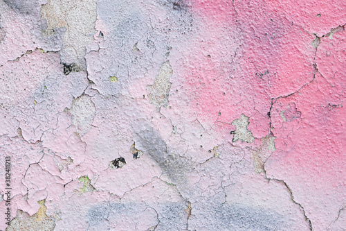 Pink spray paint on cracked rough concrete wall.