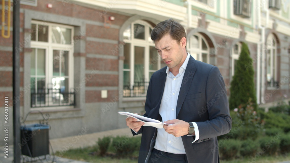 Closeup man reading documents at street. Man going to work in suit at street Closeup man reading documents at street. Man going to work in suit at street