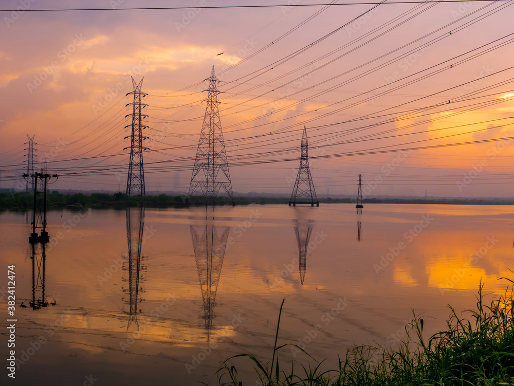 High-voltage power lines at Sunrise/sunset. .Saltpans in Mumbai.