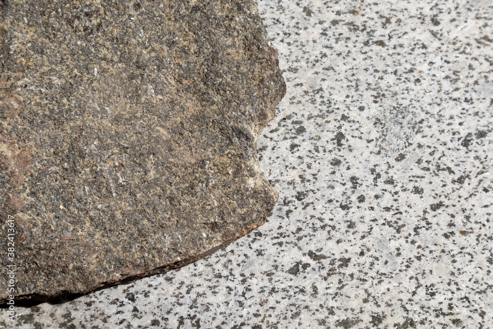 Granite stone on unpolished surface of slab with black and grey texture, selective focus. Granite stone on unpolished surface of slab with black and grey texture, selective focus.