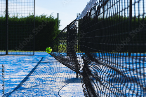 Paddle tennis outdoor court with the ball smashed  on the net