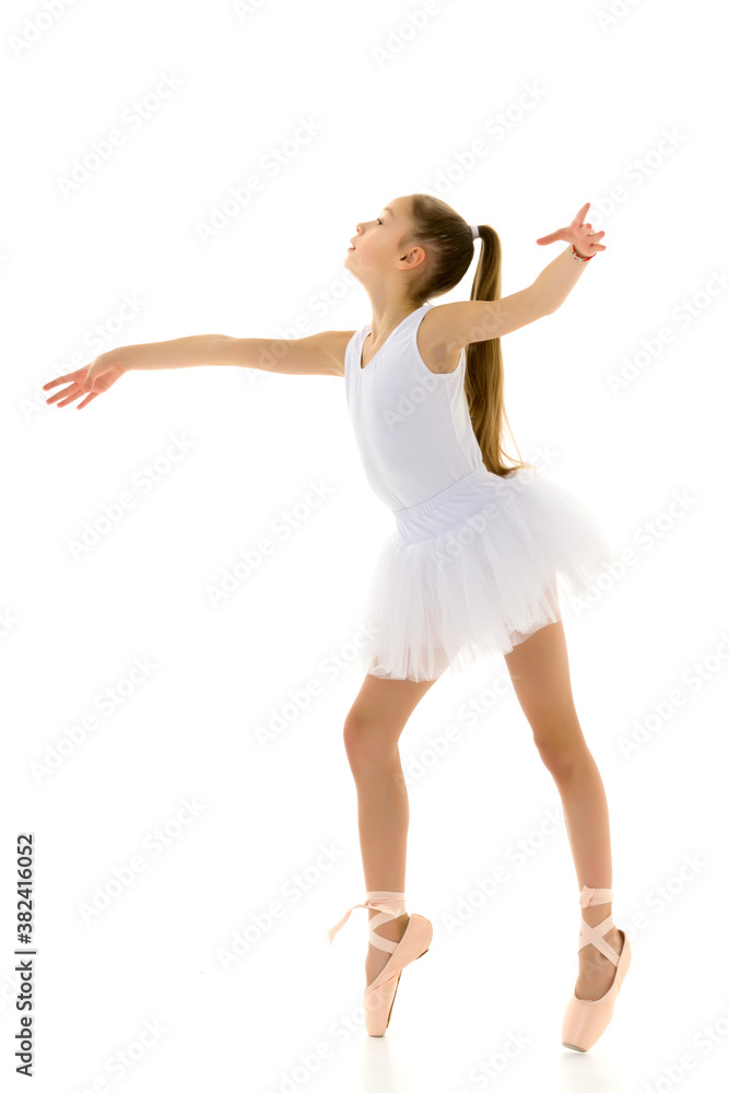 Cute little girl in a tutu and pointe shoes dancing in the studio on a white background. Cute little girl in a tutu and pointe shoes dancing in the studio on a white background.