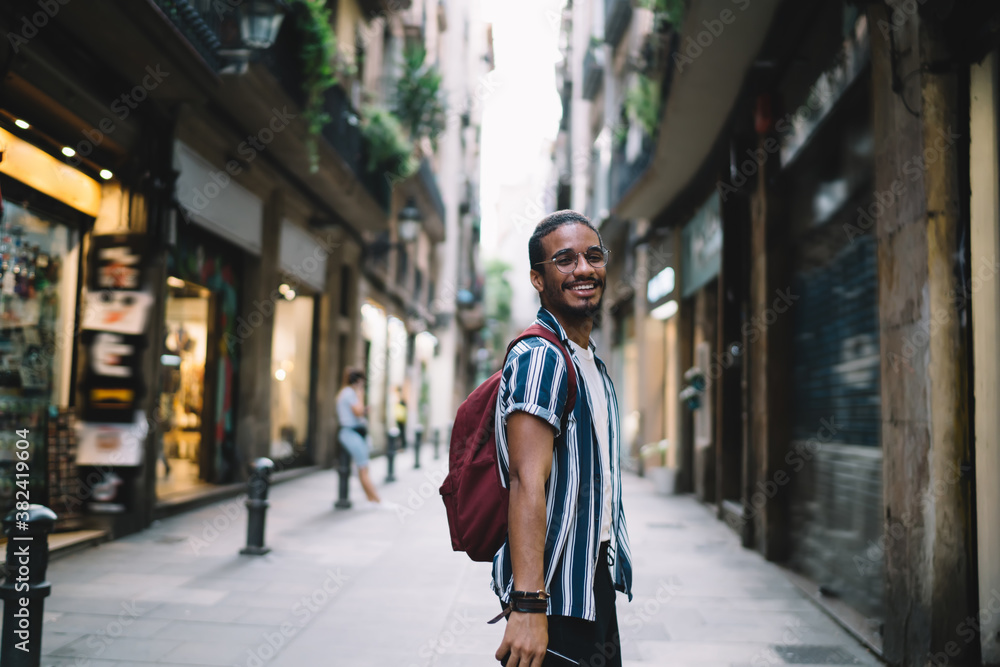 Ethnic man with backpack walking on street