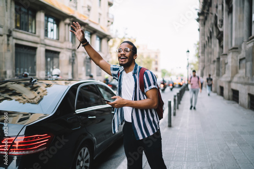 Cheerful ethnic man catching taxi