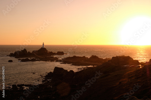 Sunset over La Corbière lighthouse, Jersey set on a tidal island, surrounded by dark rocks