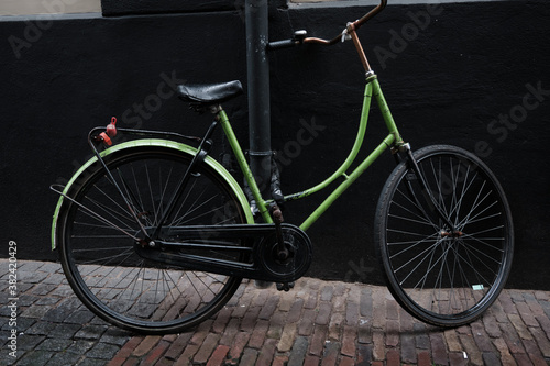 A plain green Dutch ladies bike against a black background 
