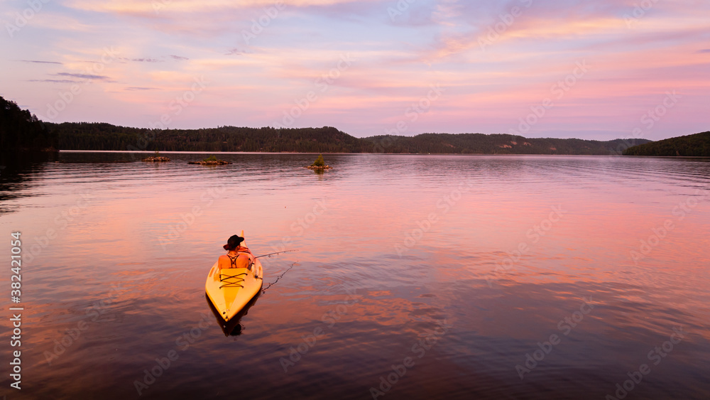 Fototapeta premium Back view of a woman fishing from a kayak on the Temiscamingue lake, Canada