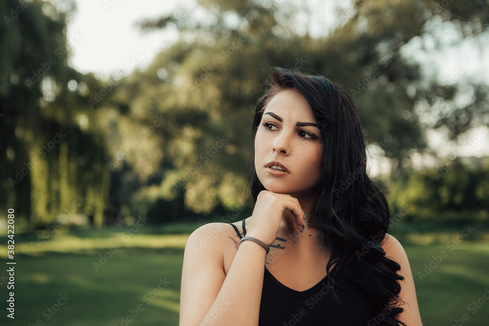 Portrait of pensive woman in singlet thinking outside, nature background with copy space.