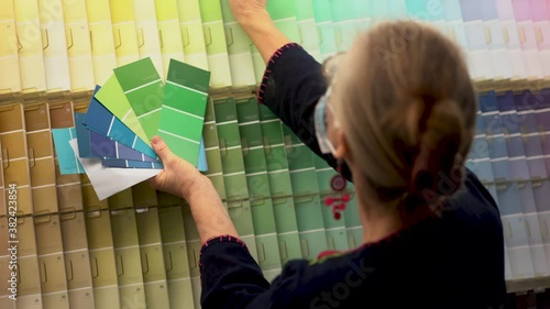 Closeup of woman wearing face mask looking at paint chips in a hardware store. Concept of cornonavirus shopping experience. photo