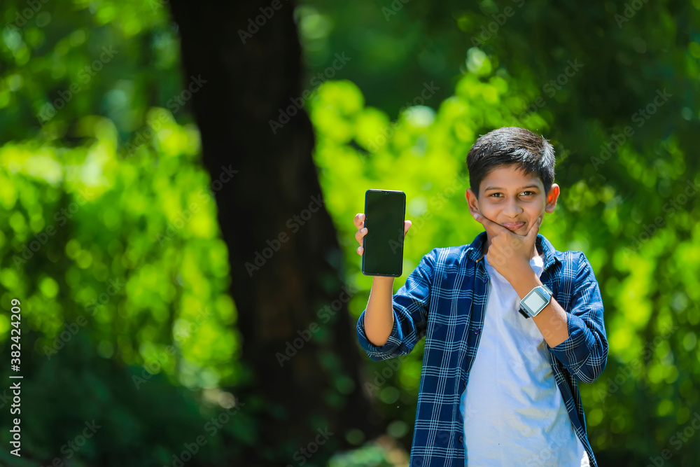 technology and people concept - smiling teenage boy in blue shirt showing smartphone with blank screen technology and people concept - smiling teenage boy in blue shirt showing smartphone with blank screen