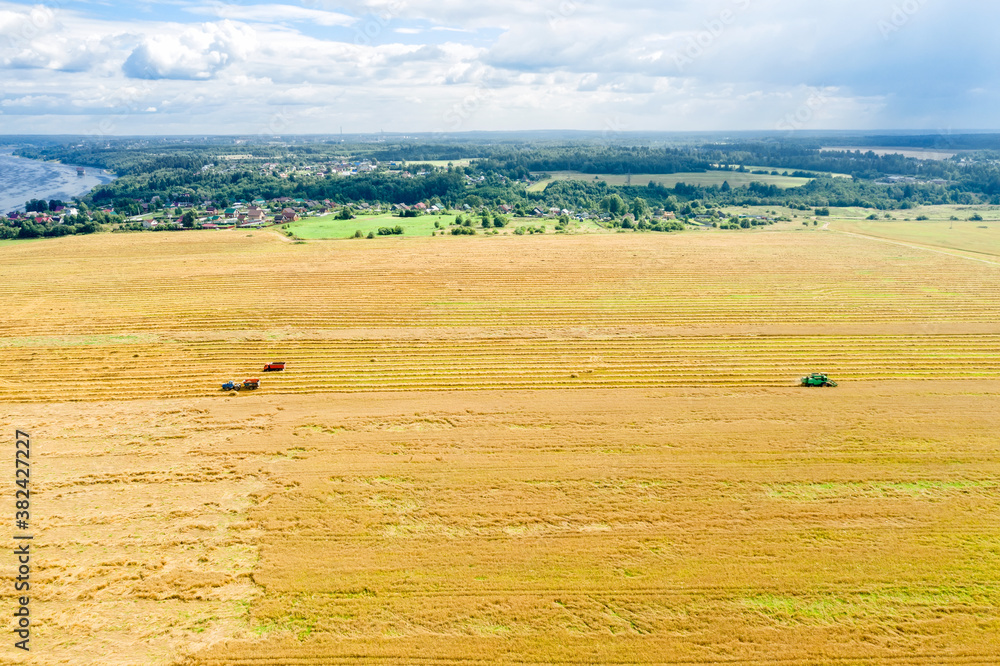 Obraz premium Top view of the field with harvesting equipment and the river leaving to the horizon