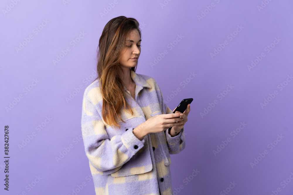 Young Ireland woman isolated on purple background sending a message or email with the mobile Young Ireland woman isolated on purple background sending a message or email with the mobile