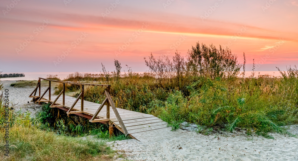 Wooden bridge at sandy beach of the Baltic Sea or coastal landscape at dawn, Europe Wooden bridge at sandy beach of the Baltic Sea or coastal landscape at dawn, Europe