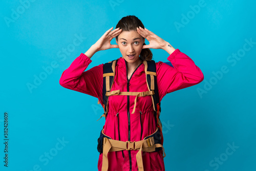 Young mountaineer woman over isolated blue background with surprise expression