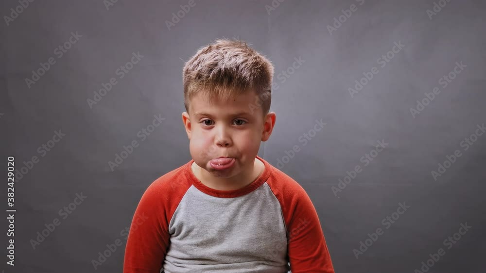 Boy shows his tongue on camera in the studio. Child sticks out his tongue. High quality. Boy shows his tongue on camera in the studio. Child sticks out his tongue. High quality.