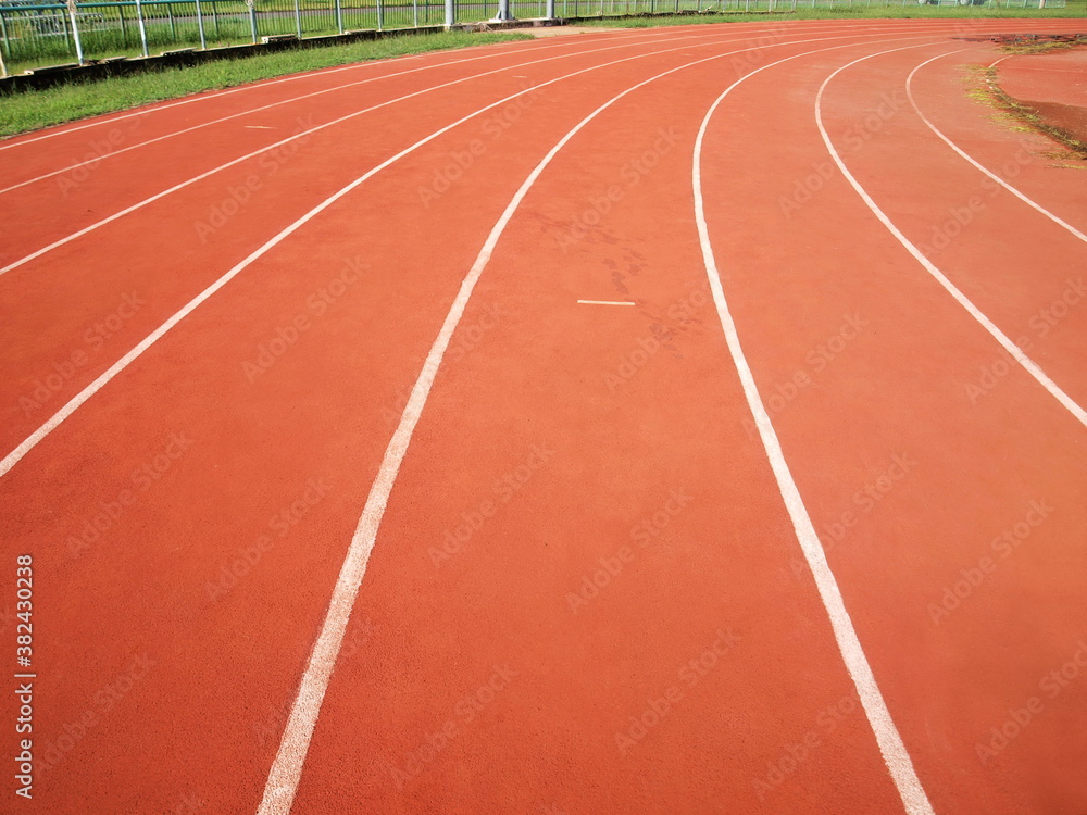 curve of running track. Tartan track in red with white lines. Selective focus