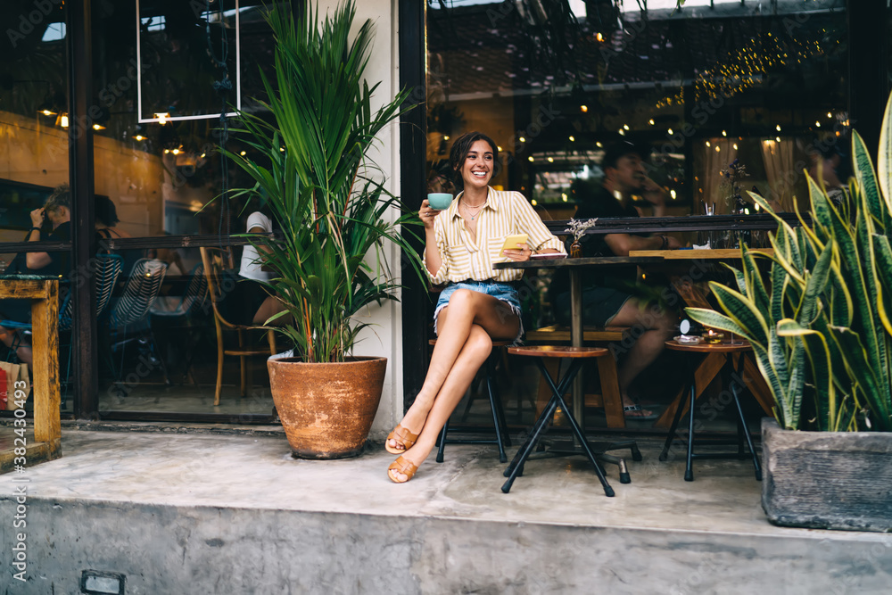 Positive woman with drink sitting at table Positive woman with drink sitting at table