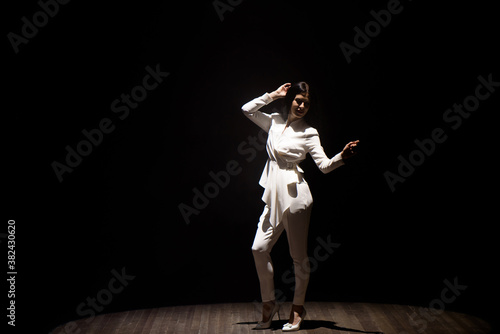 model in a white suit on stage in a beam of white light