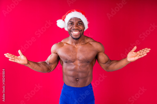 naked nude african american man holding gift box with white ribbon tie bow in red studio background photo