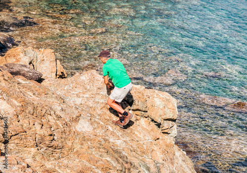 Mature man climbing on cliffs of Mediterranean Sea
