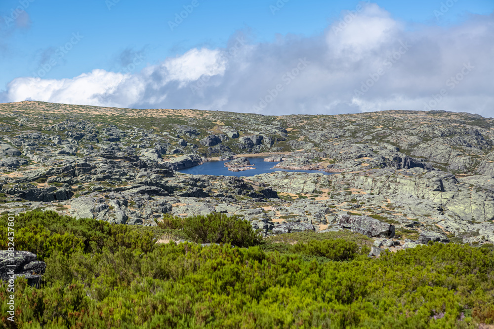 View from the top of the mountains of the Serra da Estrela natural park, Star Mountain Range, small lake, rocks and vegetation and mountain landscape