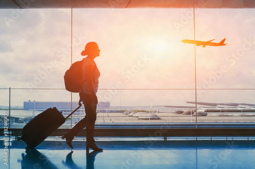 tourist travel to international airport terminal, silhouette of woman passenger with luggage suitcase