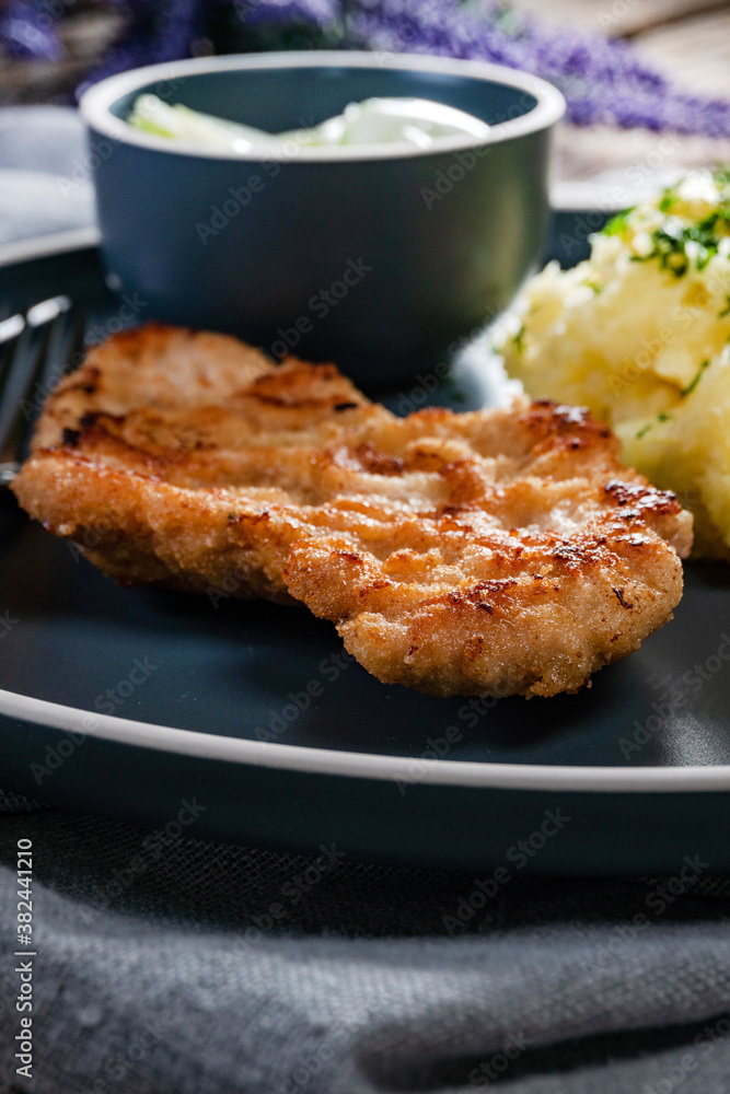 Pork chop served with mashed potatoes and cucumber salad.