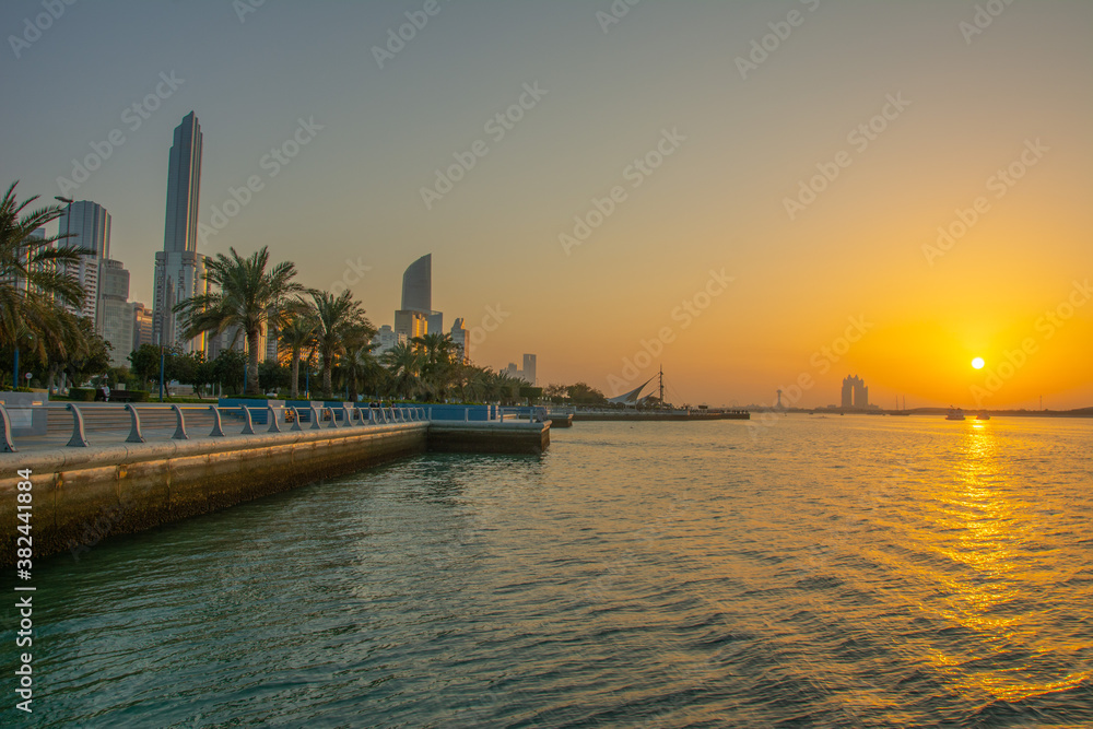 The view of the Corniche boulevard with high rises and palm trees on sunset in Abu Dhabi, United Arab Emirates The view of the Corniche boulevard with high rises and palm trees on sunset in Abu Dhabi, United Arab Emirates