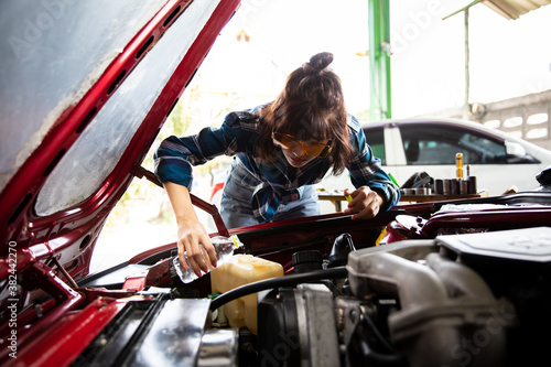 Young women fill Radiator water and fluid of car, woman pouring windshield washer fluid into car photo