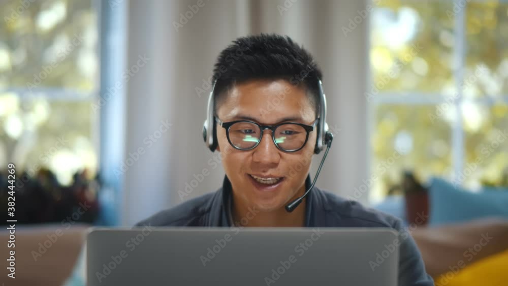 Young asian businessman working on laptop in headset having video conference at home Young asian businessman working on laptop in headset having video conference at home