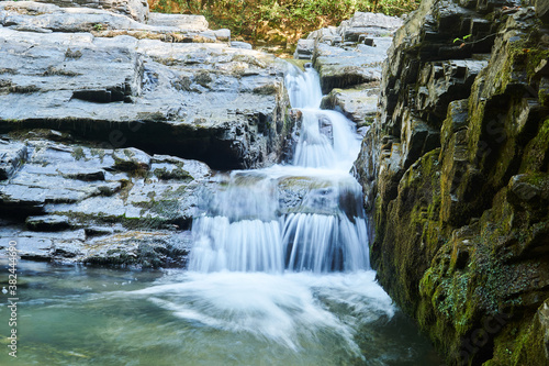 small waterfall in a mountain stream between rocks, the water is blurred in motion