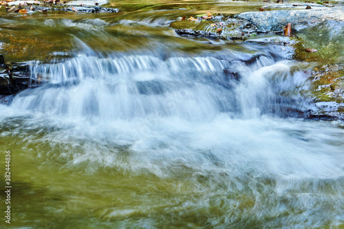 small waterfall in a mountain stream between rocks  the water is blurred in motion
