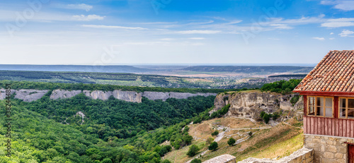 Panoramic picture. The valley of Josaphat. On the right is the rocky medieval cave town of Chufut-Kale. Next, the Assumption Rock. In the distance the city of Bakhchisaray. Republic of Crimea. photo