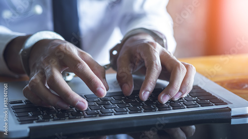 Hands of hacker with handcuffs above notebook keyboard, punishment for cybercrime, business concept.