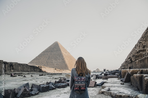 A European blonde walks near the pyramids in the desert in Cairo. The girl against the background of ancient buildings in Giza.