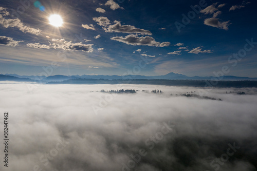 Obraz na płótnie Sun beams above the fog and clouds in the blue sky forest tops sticks through the fog. w salonie