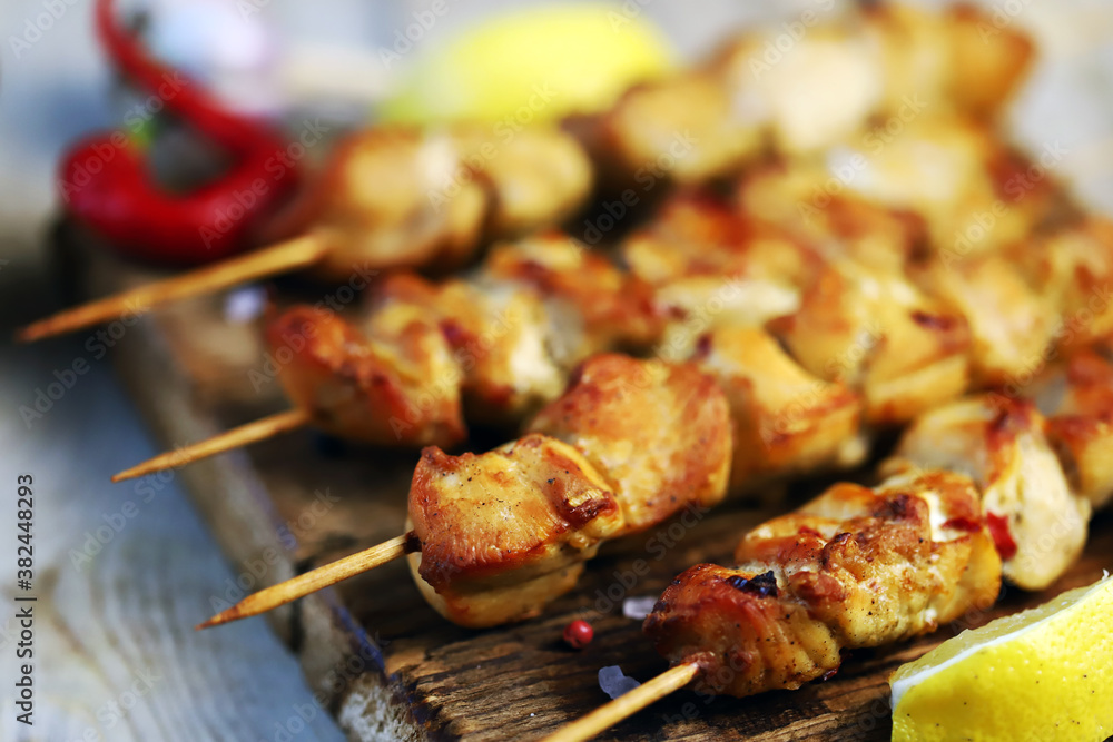 Selective focus. Chicken skewers on wooden sticks. Appetizing mini kebabs on a wooden board.