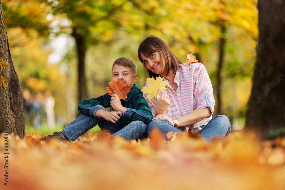 Mom and son are sitting on the ground in a beautiful autumn forest. Love and tenderness. Mom and son are sitting on the ground in a beautiful autumn forest. Love and tenderness.