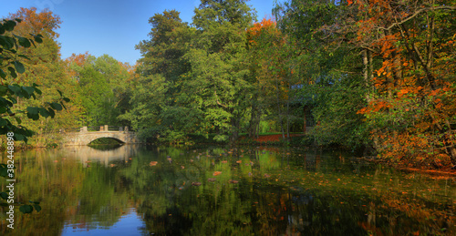 Autumn landscape with a picturesque pond and a stone bridge