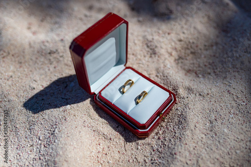 Fotografie Close up view of wedding rings inside the red wooden box on the white sand of Ca