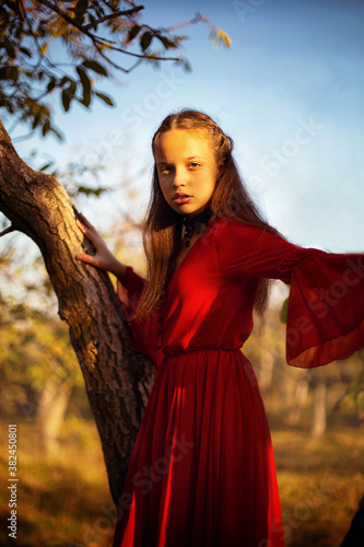 Girl in the autumn forest in a long red dress
