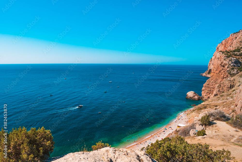 Panoramic view of the picturesque beach with white sand and azure water, top view of the beach vacationers, Crimea