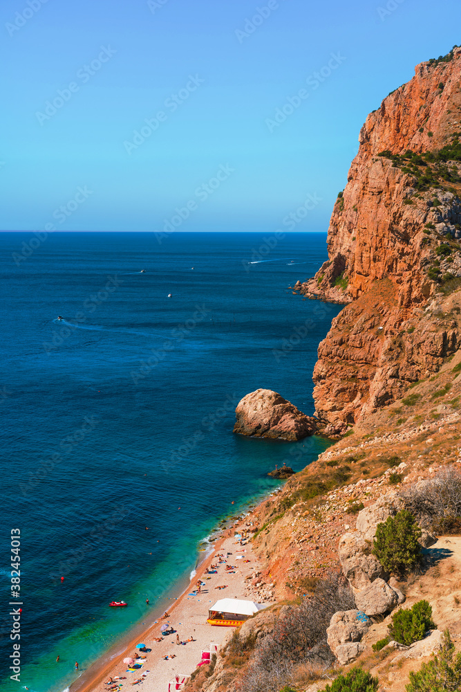 Panoramic view of the picturesque beach with white sand and azure water, top view of the beach vacationers, Crimea