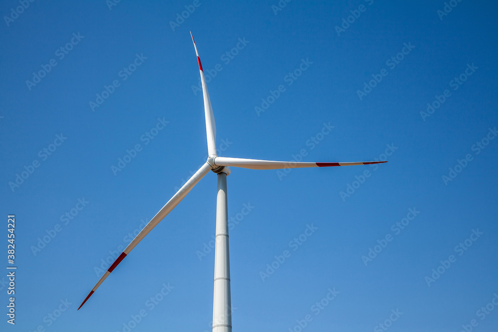 Wind turbine for electricity generation, renewable energy on a blue sky background