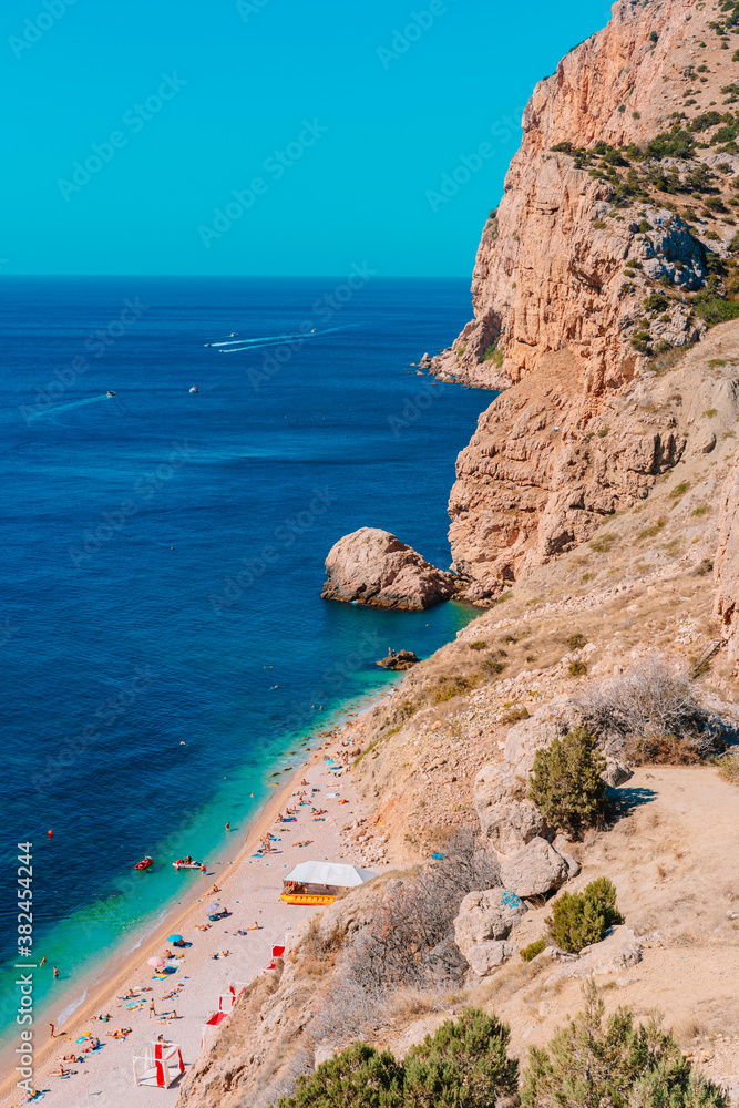 Panoramic view of the picturesque beach with white sand and azure water, top view of the beach vacationers, Crimea
