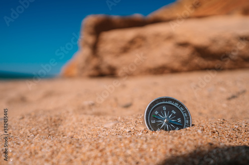 Background image of compass lying in the sand on the beach with sea view, vacation and travel concept