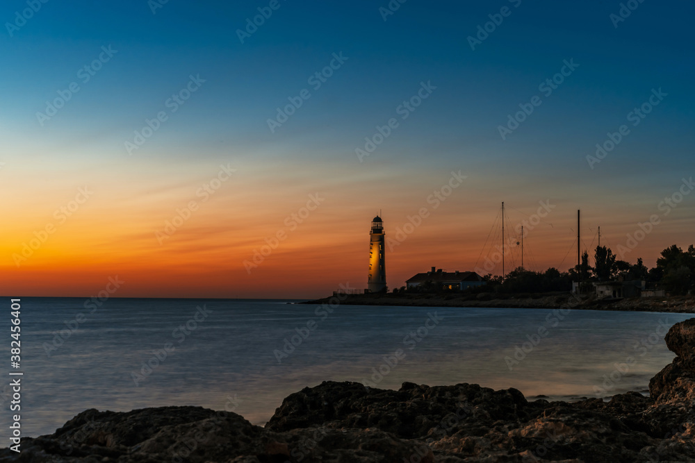 Romantic view of the lighthouse from the cliff at sunset